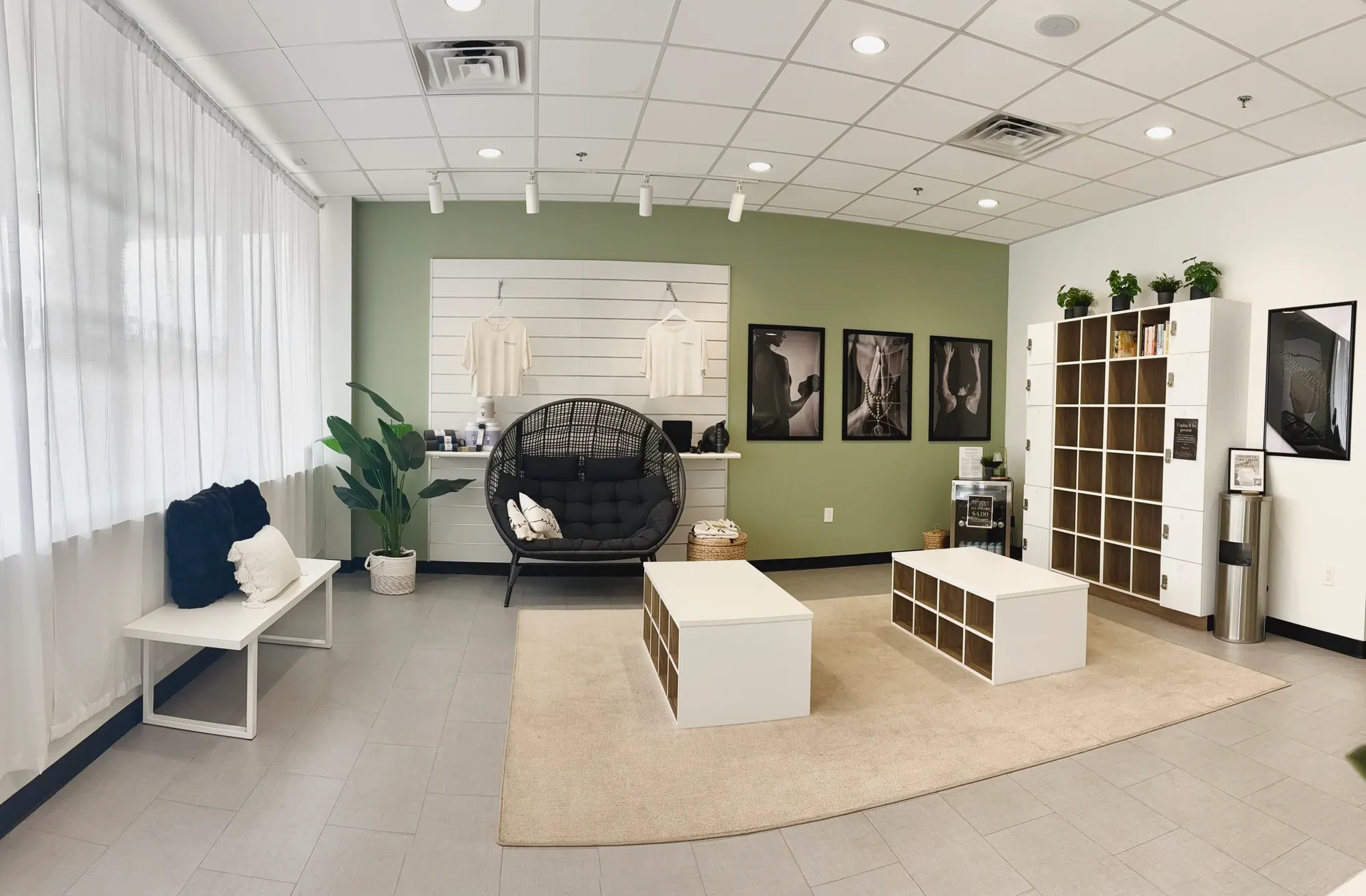 The MonmouthFlow lounge: a woven egg chair, white cubby benches, and a wall of branded apparel